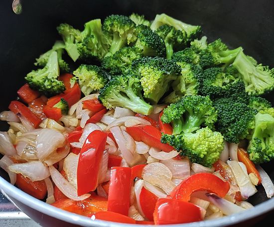 adding steamed broccoli to the pan for making galette recipe