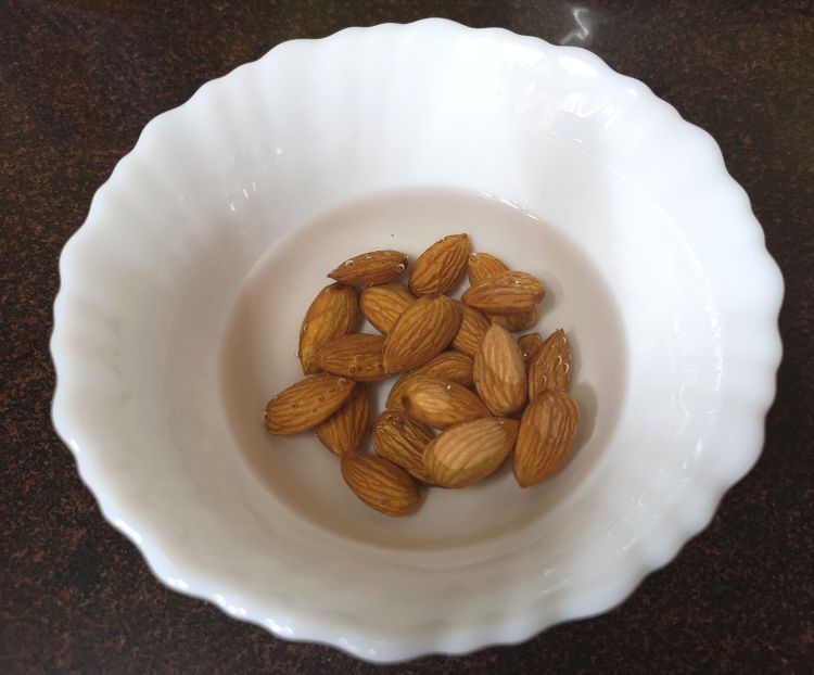soaking almonds in warm water in a white bowl for kesar badam doodh, saffron almond milk recipe, benefits of badam, almond