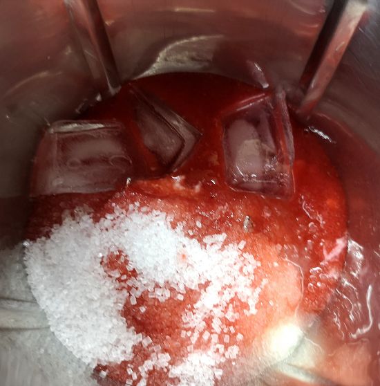 Adding ice cubes to the strawberry lassi