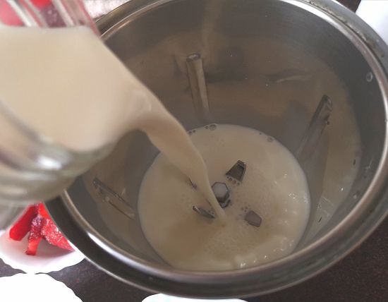 adding cold milk to the blender for preparing strawberry milkshake