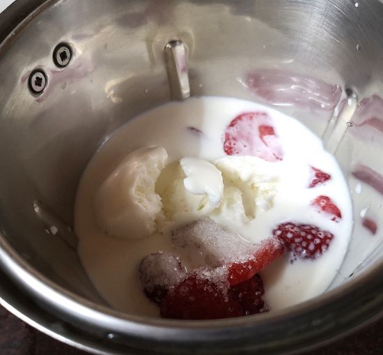 vanilla ice cream , cold milk, sugar and strawberries ready to be blended