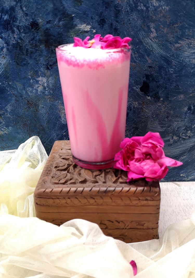 close up photo of Rose Milkshake, drizzled with rose syrup, topped with rose petals, served in a glass 
