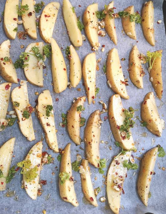 placing all the potato wedges coated with seasoning into the oven tray lined with parchment paper, ready to be baked