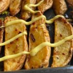 Crispy Garlic Potato Wedges, close up view of Baked Garlic Potato Wedges drizzled with spiced mayonnaise