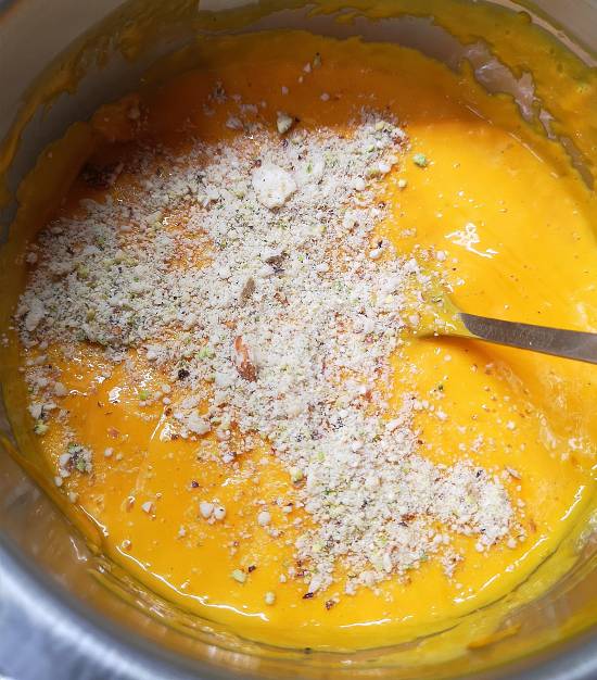 adding dry fruits powder into mango pulp, reaady to be poured into matkas
