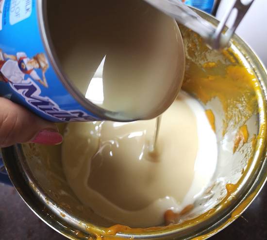 No cook mango matka kulfi recipe, adding condensed milk to mango pulp fpr preparing mango matka kulfi