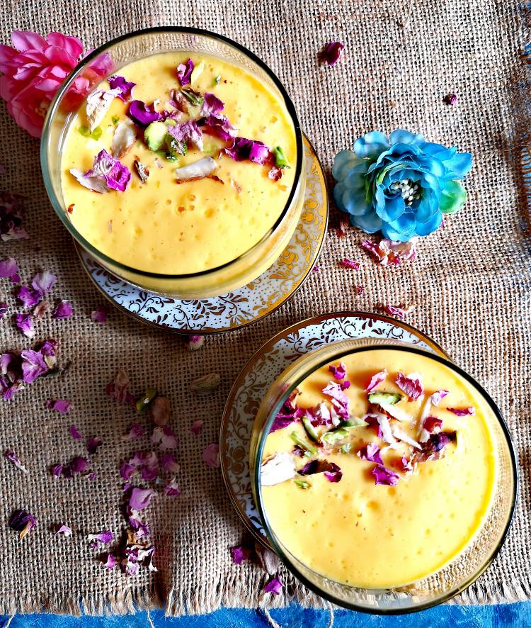 overhead photo of mango lassi served with pistachios and dry rose petals