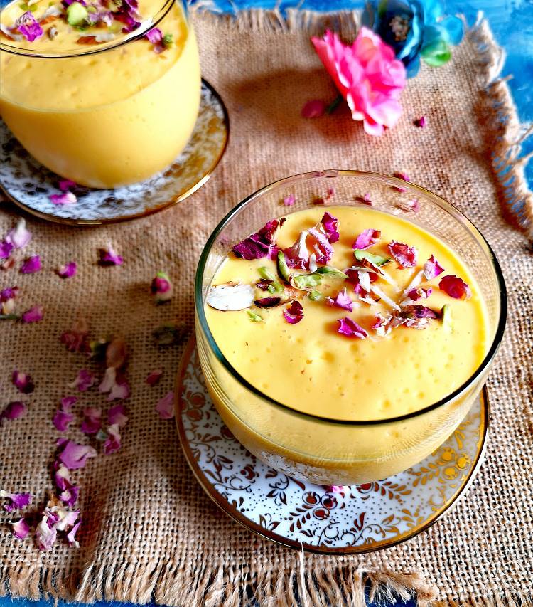 Mango Lassi served in glasses and garnished with pistachio flakes and dry rose petals