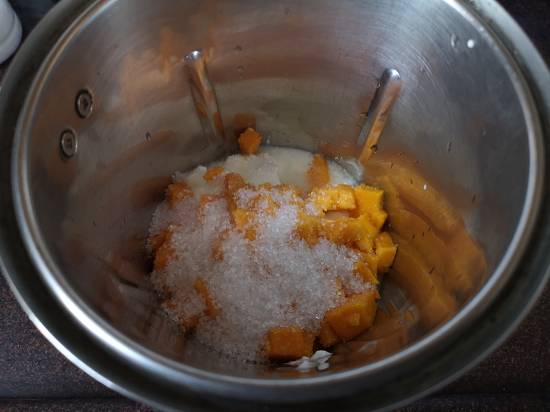 adding mango chunks and sugar into the blender for Mango Lassi